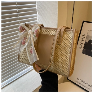 Detail of straw tote bag featuring leather trim and pink flower embroidery lace bow