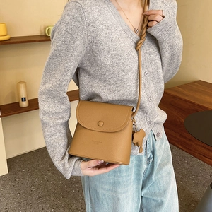 Brown textured leather crossbody bag with knot shoulder strap and elephant charm pendant