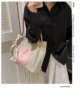 Detail of woven straw tote bag with pink handles and Summer leather patch detail
