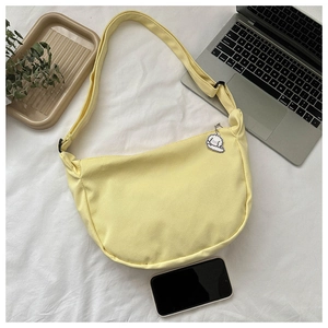 Detail of light yellow crescent canvas bag with a cute puppy keychain on a laptop background