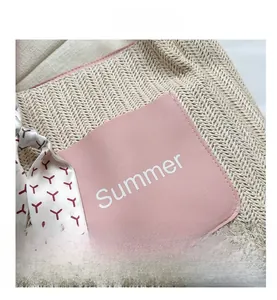 Close-up of woven tote bag featuring a pink leather patch with Summer print and silk scarf