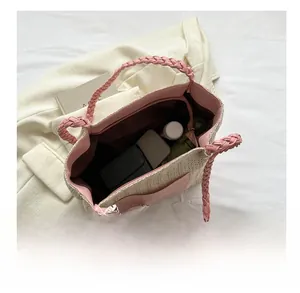 Detail shot of the spacious woven tote bag interior showing phone, wallet and water bottle