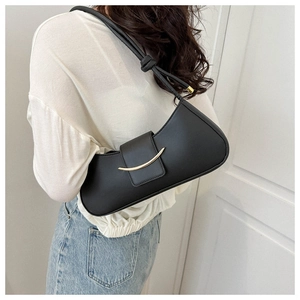 Close-up of a black leather crescent underarm bag with a gold metal buckle detail
