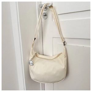 Détail du sac bandoulière en toile gaufrée crème avec sangle réglable et pendentif chien