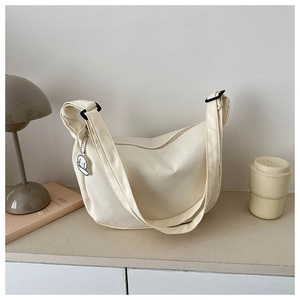 Detail of waffle textured off-white crossbody bag with cute poodle plush charm