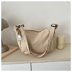 Detail of waffle texture beige crescent bag with adjustable strap and cute charm
