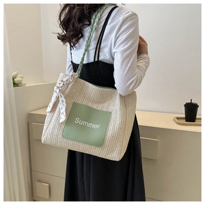 Close-up of woven straw tote bag with green Summer patch and decorative silk scarf