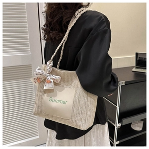 Detail of a beige woven straw tote bag with Summer patch and floral scarf on strap
