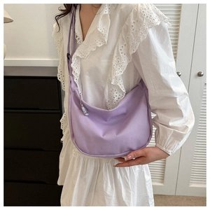 Detailed texture of purple corduroy crescent bag with silver zipper and shoulder strap