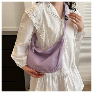 Detail view of light purple waffle fabric crescent bag with white cartoon charm on strap