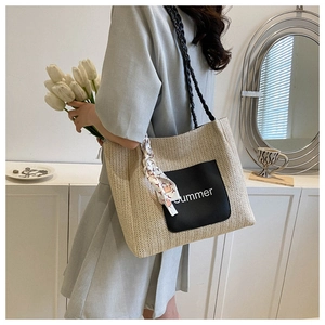 Close-up of beige woven tote bag with black summer text patch and colorful silk scarf