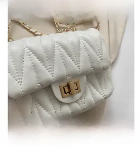 Detail of white quilted crossbody bag with V-shaped stitching and gold rotary lock