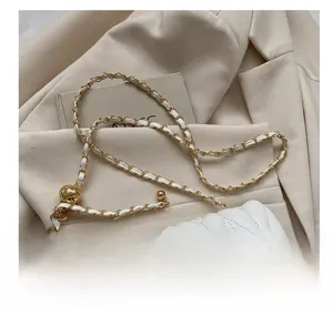 Detailed shot of white quilted leather bag featuring gold ball chain adjuster and metal lock