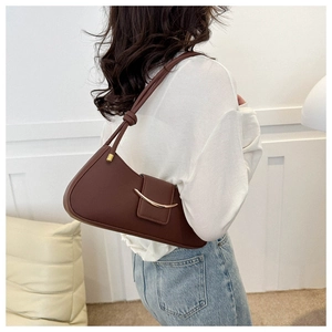 Detail of dark chocolate leather shoulder bag with gold metal trim and knotted strap