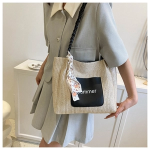 Detail of woven tote bag with a black leather pocket and decorative printed silk scarf