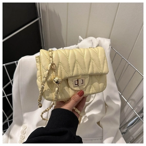 Detail of light yellow quilted shoulder bag with V-stitch and gold chain strap