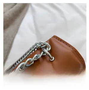 Macro detail of brown quilted leather handbag with silver chain hardware connection
