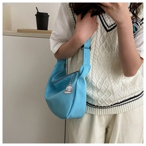 Close-up of light blue crossbody bag with adjustable strap and cute puppy pendant