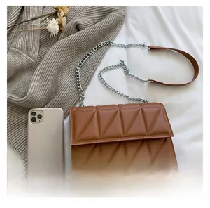 Detailed view of caramel brown quilted crossbody bag with silver chain and leather strap