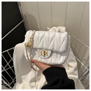 Close-up of white crossbody bag with V-shaped quilting, gold chain and twist lock clasp