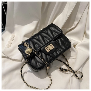 Detail of black quilted crossbody bag with gold chain strap and spherical charm