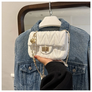 Close-up of white quilted leather crossbody bag with gold chain and metal buckle