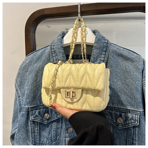 Detail of yellow quilted leather crossbody bag with gold chain strap and turn-lock