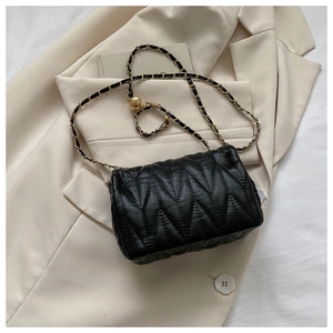 Detail of black V-quilted leather bag with golden chain and metal adjustment ball