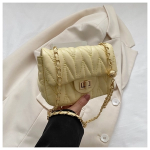 Detail of cream quilted PU leather bag featuring gold adjustable ball chain and metal lock