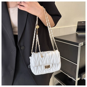 Close-up of white quilted chain bag with gold metal buckle and adjustable ball strap
