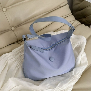 Light blue nylon crescent hobo bag on textured white fabric and beige sofa background