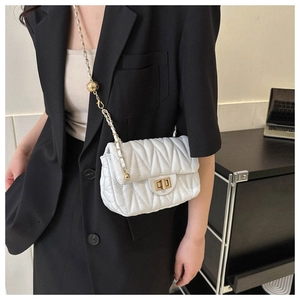 Detail of white quilted crossbody bag with golden chain strap and adjustable metal ball