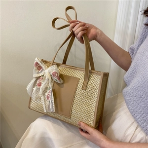 Large straw beach tote bag with a white lace bow and brown leather handles for women