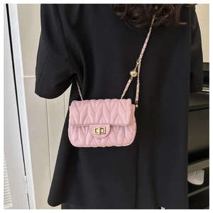 Detailed view of pink quilted handbag with gold chain strap worn over a black blazer