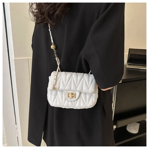 Detail of white quilted crossbody bag with golden chain and adjustable ball buckle