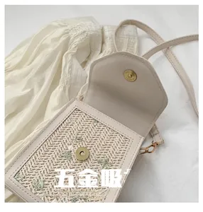 Detail of the golden magnetic buckle closure on a beige woven floral crossbody bag
