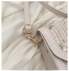 Detail of light gold hardware hooks and adjustable leather strap on woven crossbody bag
