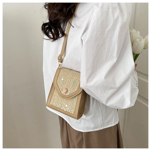 Close-up of woven straw mini bag with delicate white floral embroidery and retro clasp