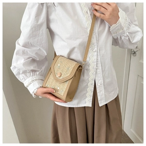 Detail of hand-woven straw bag with premium brown leather trim and round decorative button