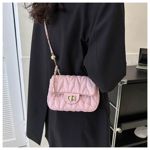 Detail of pink quilted shoulder bag with V-shaped stitching and golden chain strap