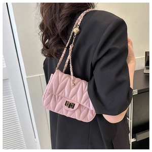 Macro shot of pink quilted leather bag with V-shaped stitching and gold twist lock