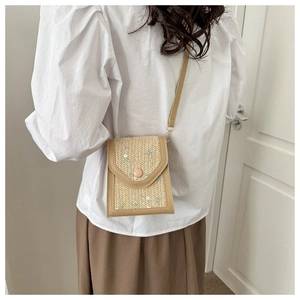 Detail of woven crossbody phone bag with leather trim and floral embroidery accents