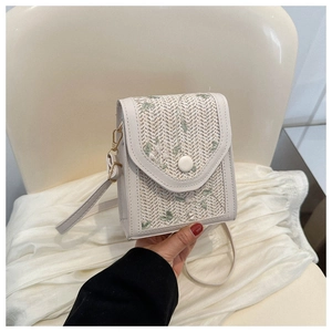 Detailed close-up of woven white phone bag featuring delicate green floral embroidery