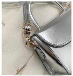 Close-up of golden metal hooks and adjustable hardware on silver crossbody bag
