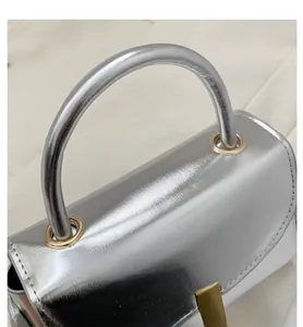 Detail of silver metallic leather handbag featuring golden hardware and pleated texture