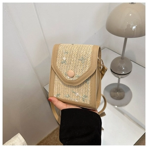 Detail of woven straw phone bag with floral embroidery and brown leather trim