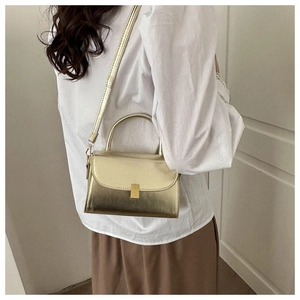 Detail of metallic gold crossbody bag with rectangle clasp worn with a white shirt