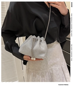 Detail of silver rhinestone bucket bag featuring pearl drawstring and metal chain strap