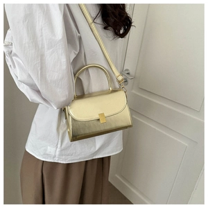 Golden metallic mini crossbody bag shown on model with adjustable strap and top handle