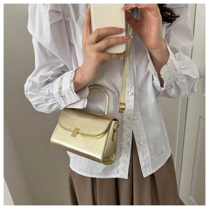 Mirror selfie showing the scale of the gold metallic mini crossbody bag with a square buckle